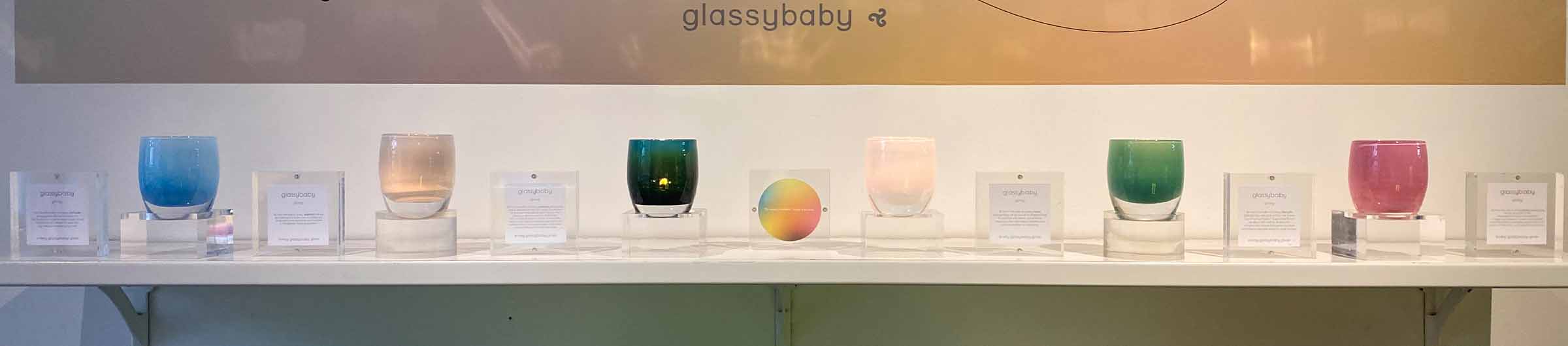 giving wall collection in store on shelf with descriptive plaques, a collection of hand-blown glass votive candle holders.