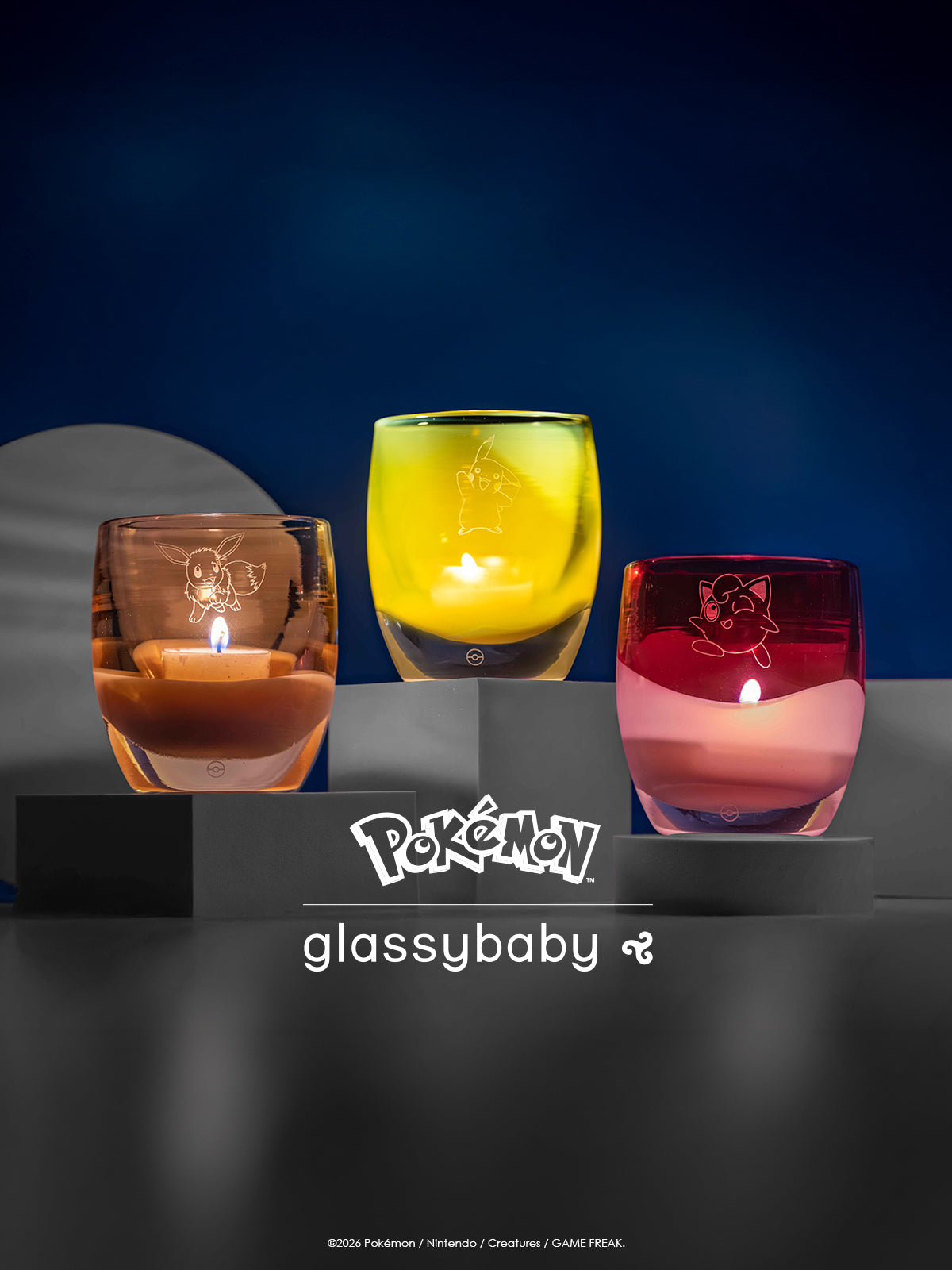 Three colorful glass candles with lit candles on a dark surface, featuring Pokémon.