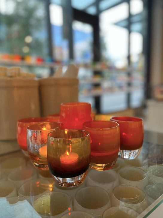 autumnal arrangement of glassybaby, hand-made glass votive candle holders on a glassybaby store table.