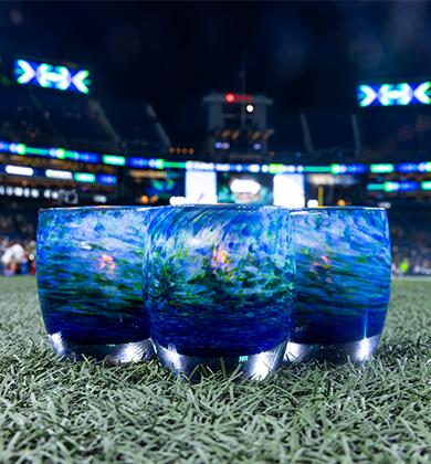 three throwback blue green textured hand-blown glass votive candle holders on stadium field.