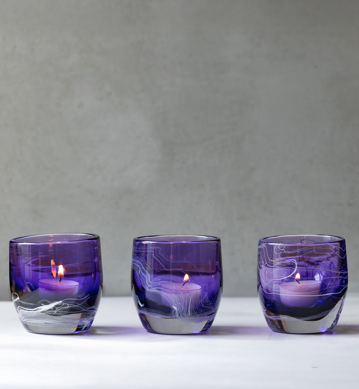 glassybaby + Simon Waranch three lit 'one of one' on white surface with gray background