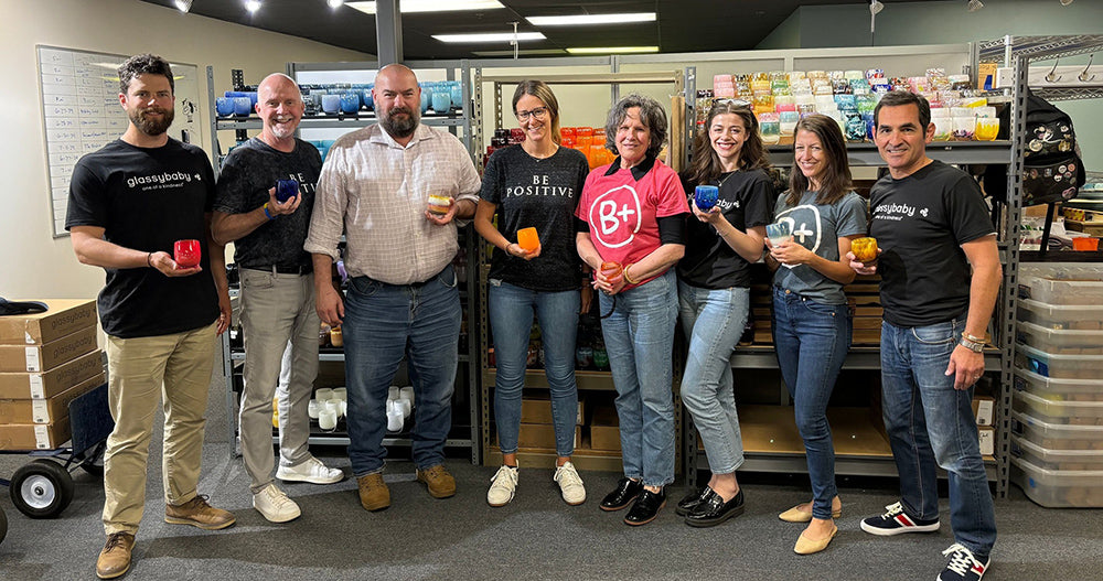 glassybaby family with The B+ Foundation family, each holding a glassybaby votive at the glassybaby headquarters.
