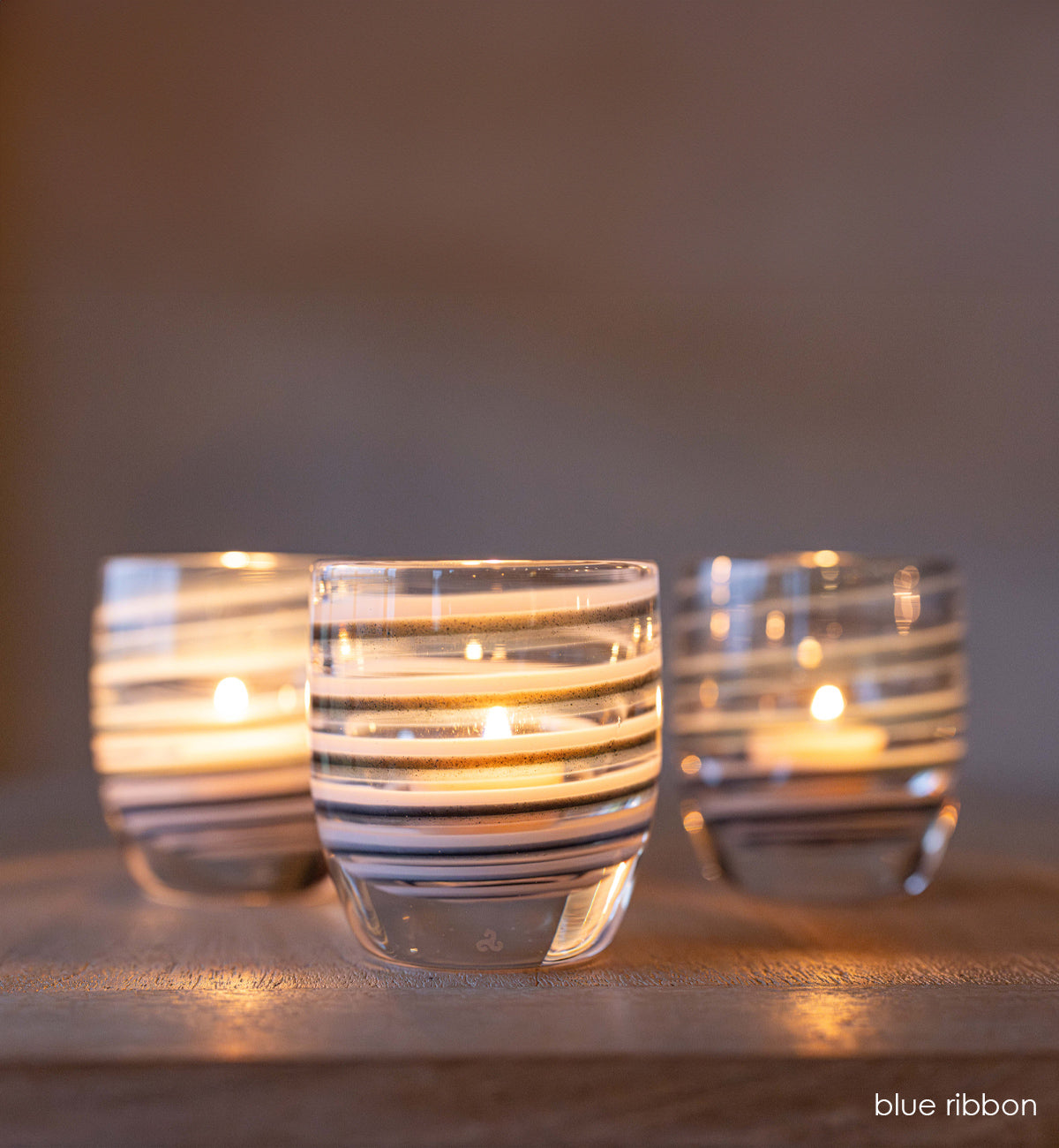 three lit 'blue ribbon' blue, white, and clear swirls hand-blown glass candle holder | glassybaby