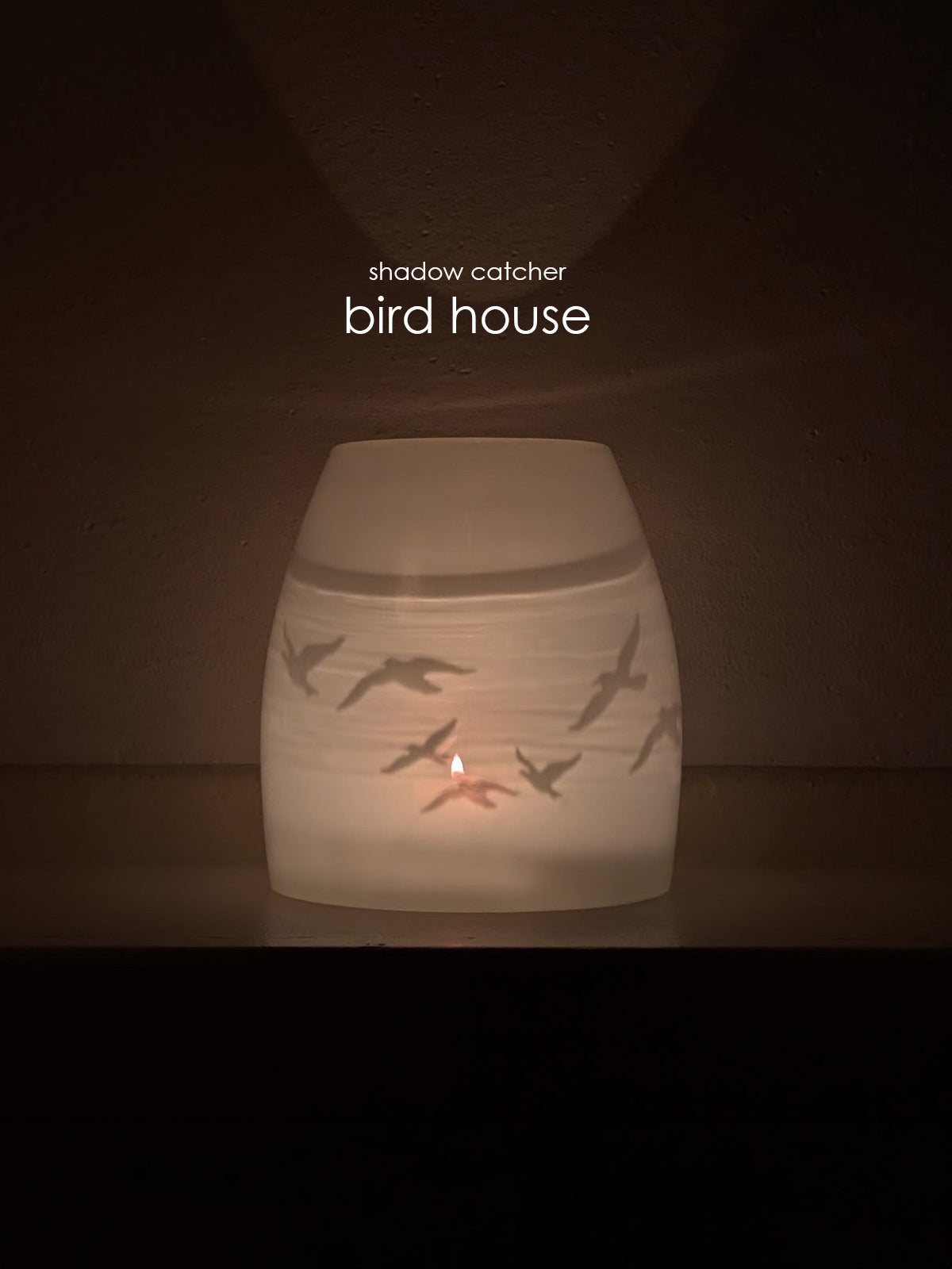 'shadow catcher bird house' : hand-blown glass candle votive with birds etched on it. covered by glass cover on a dark background