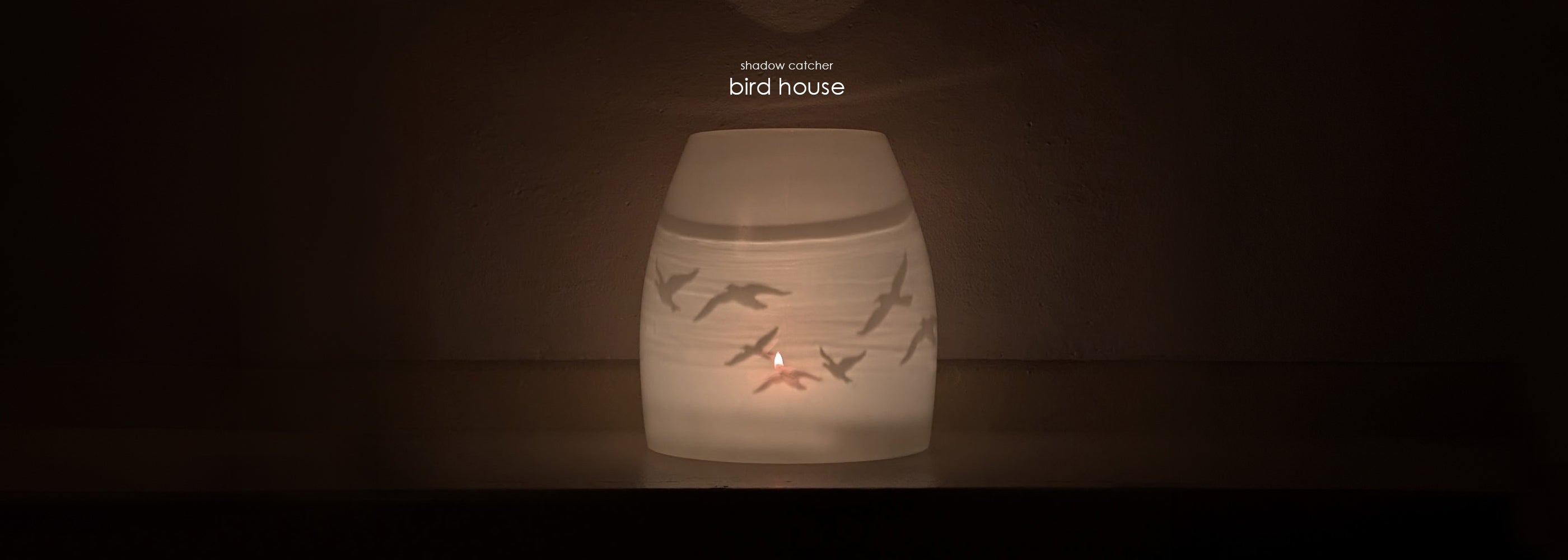 'shadow catcher bird house' : hand-blown glass candle votive with birds etched on it. covered by glass cover on a dark background