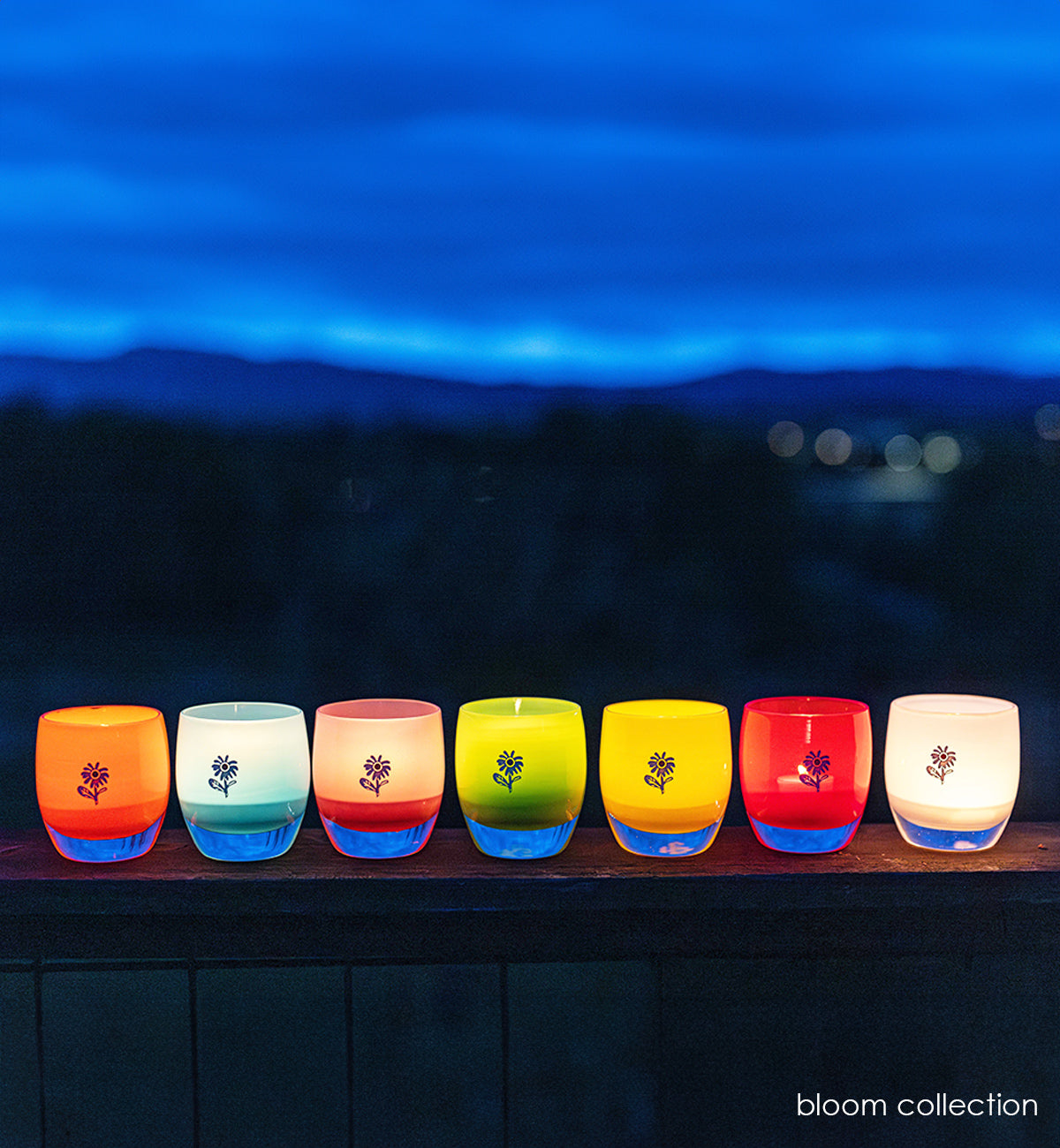 7 colorful glassybaby from the bloom collection lit at night.
