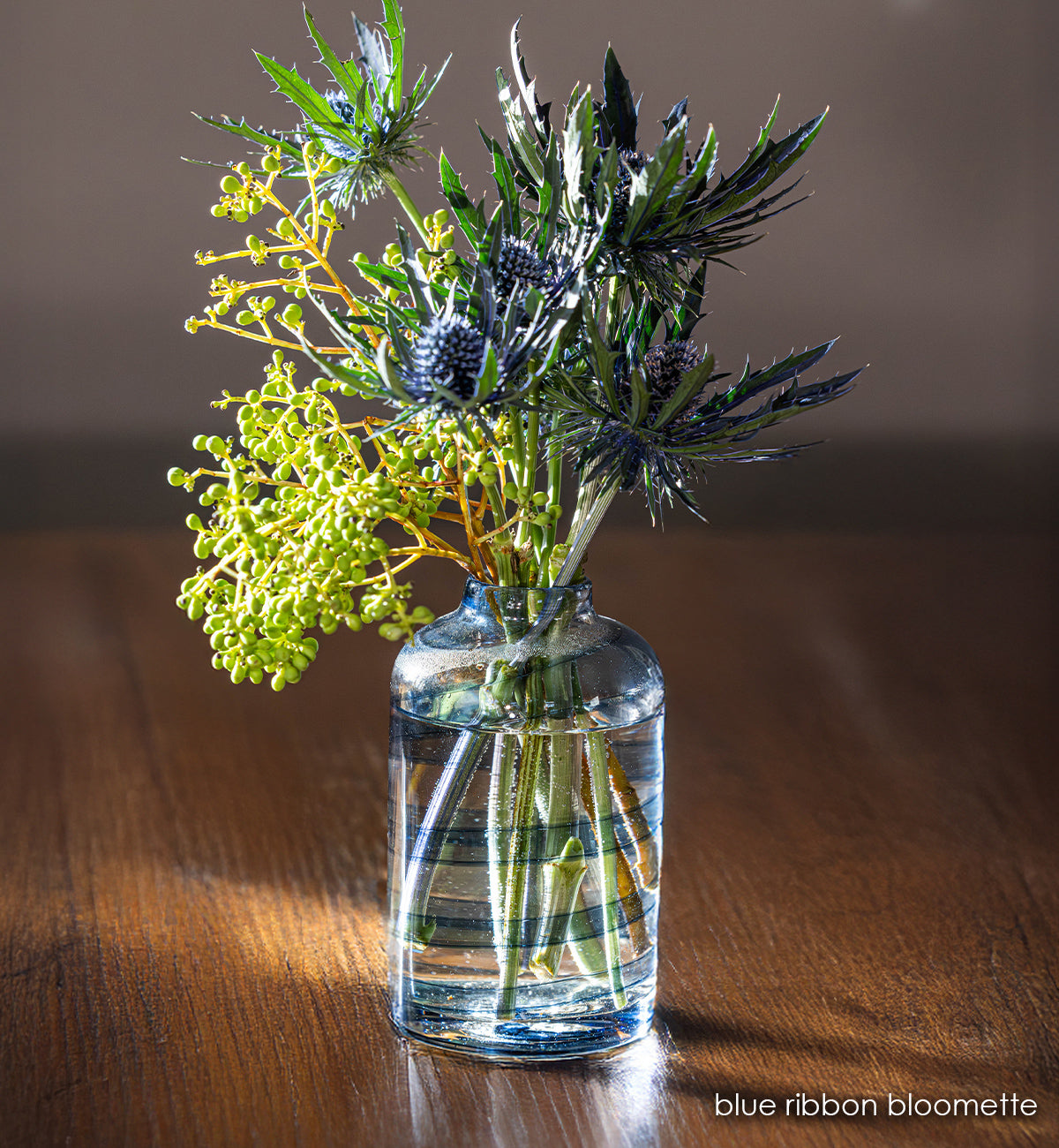 clear handblown glass bloomette with blue twisted around it. with blue flowers in vase.