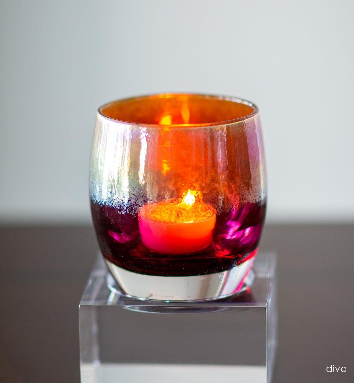 diva metallic gold on deep pink hand-blown glass votive candle holder on a reflective surface