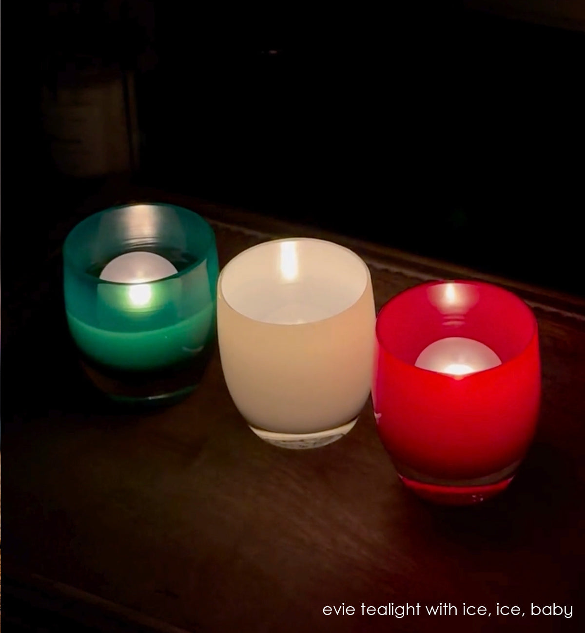 lit evie tealights with ice, ice, baby on wood dresser in the dark