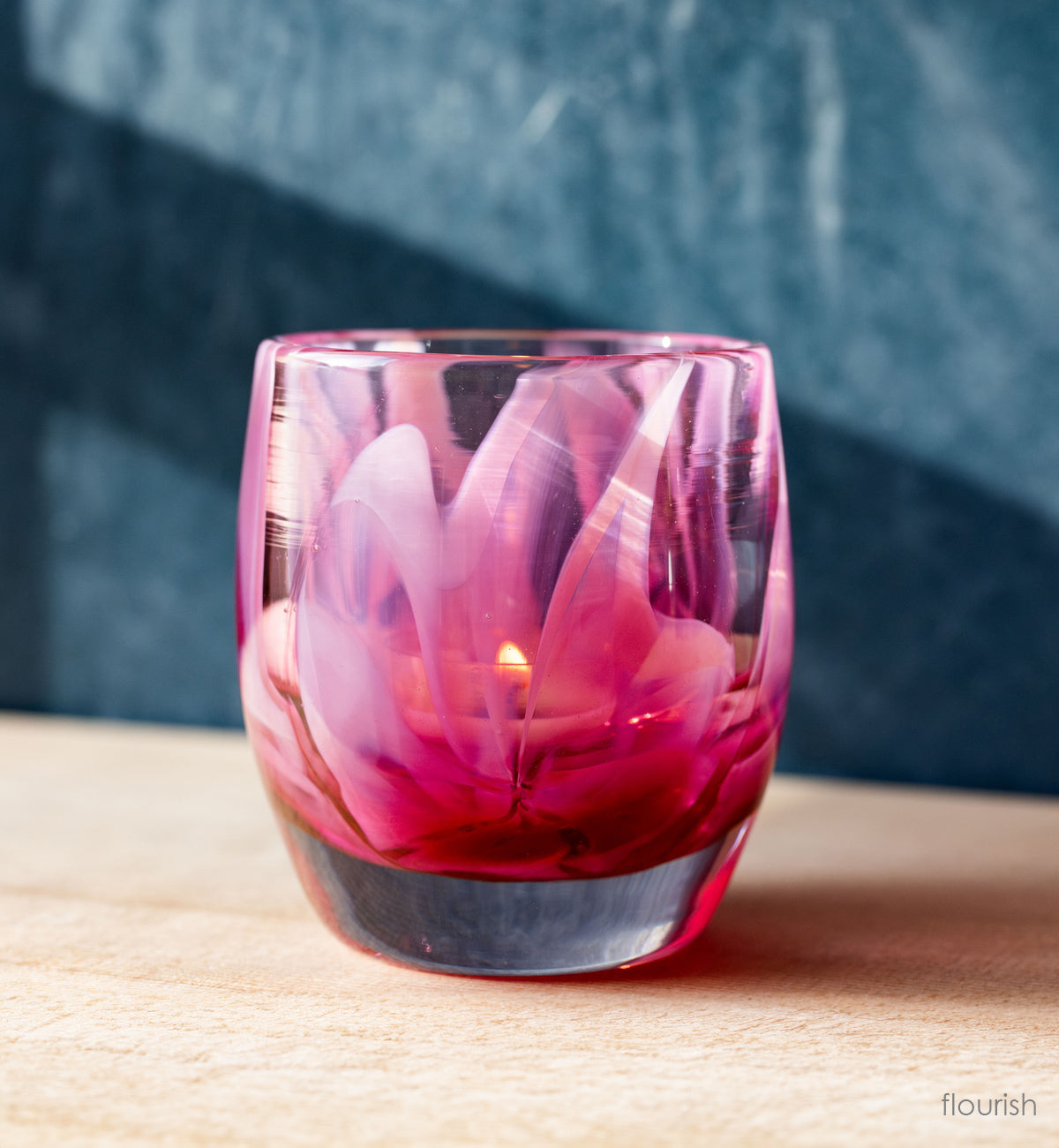 beautiful pink hand-blown glass murrini style candle holder on wood shelf