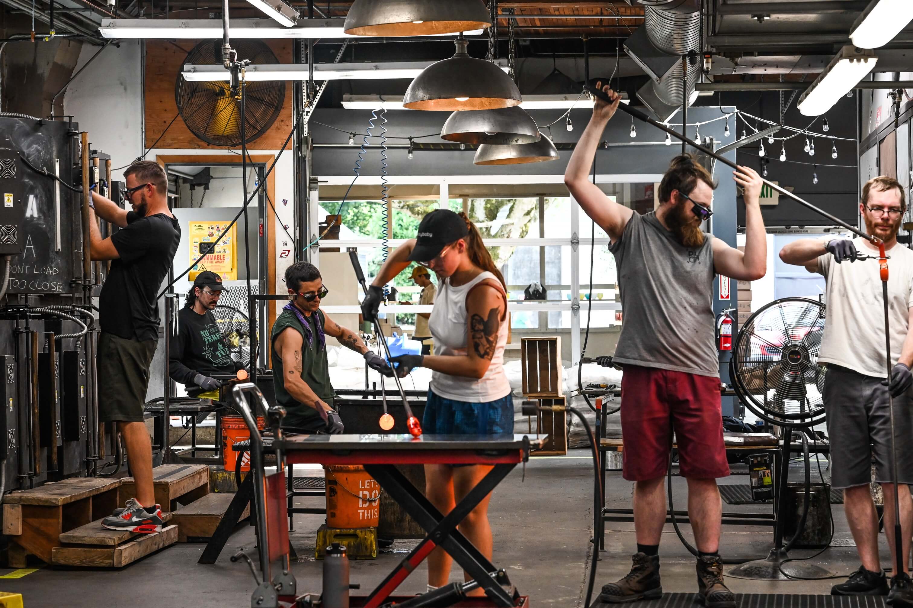 glassblowers working in glassybaby hotshop, performing different steps of glassblowing process.