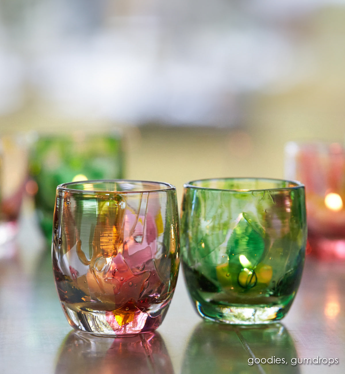 goodies glassybaby, pink and yellow shards melted into clear hand-blown glass candle holder next to gumdrop glassybaby, green shards melted into clear hand-blown glass candle holder