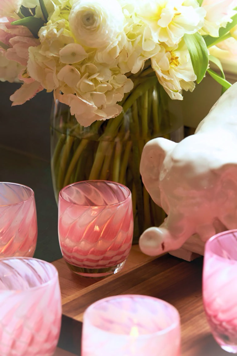 harmony, pink feathered texture hand-blown glass votive candle holder. In a lit kitchen display adorned with a ceramic elephant and a white bouquet.