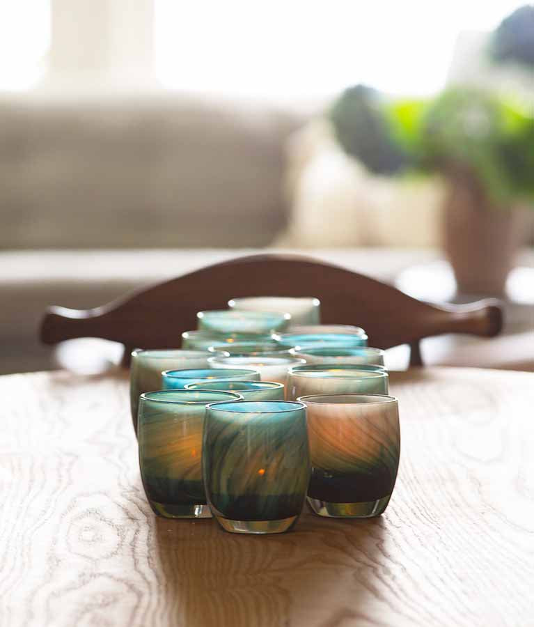 homerun glowing a little flame on a sunny wooden dining table. Hand-crafted glass votive candle holder.