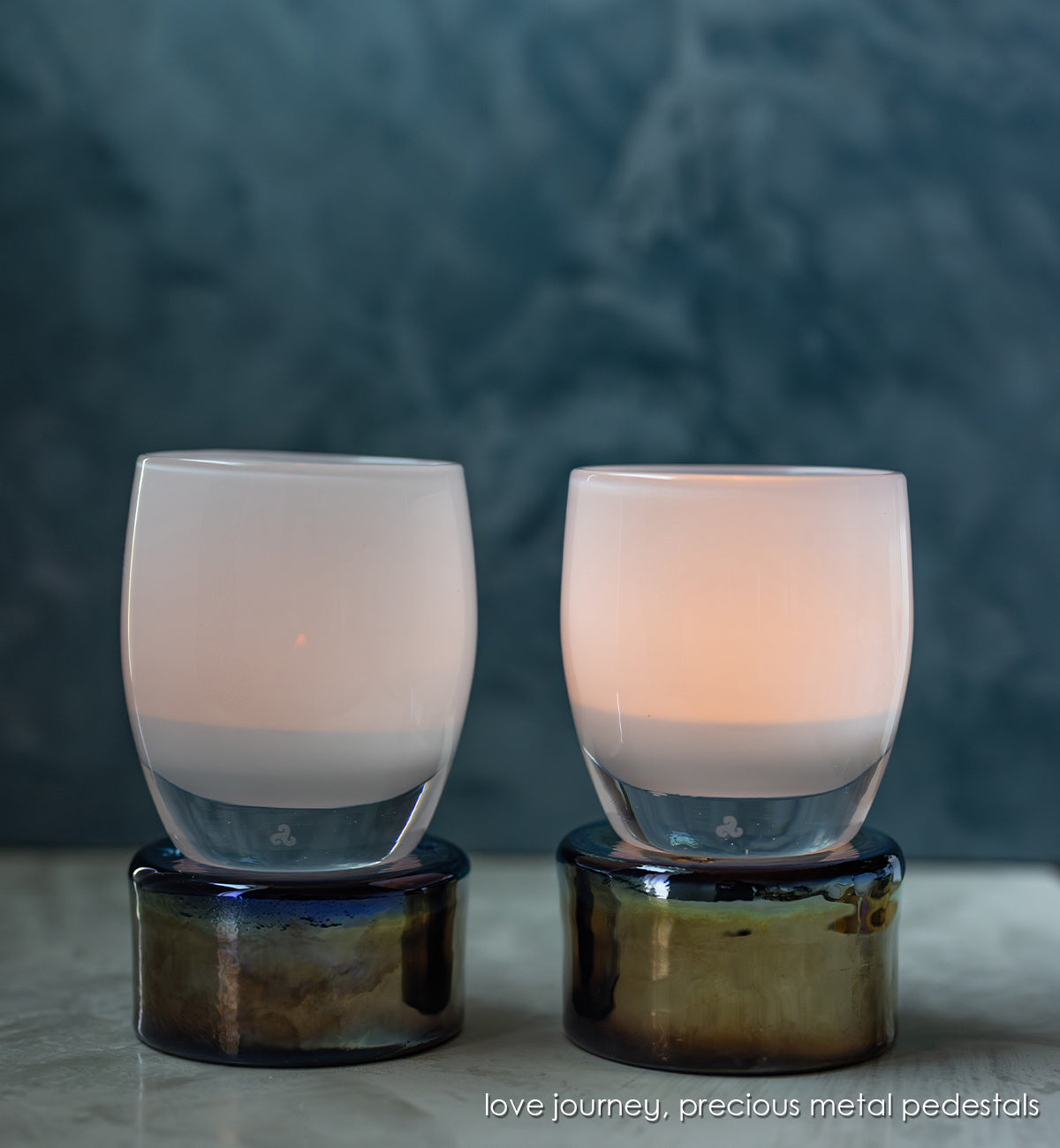 love journey set includes a cherish and a celebrate glassybaby. white lit hand-blown glass candle holders on top of precious metal pedestals.