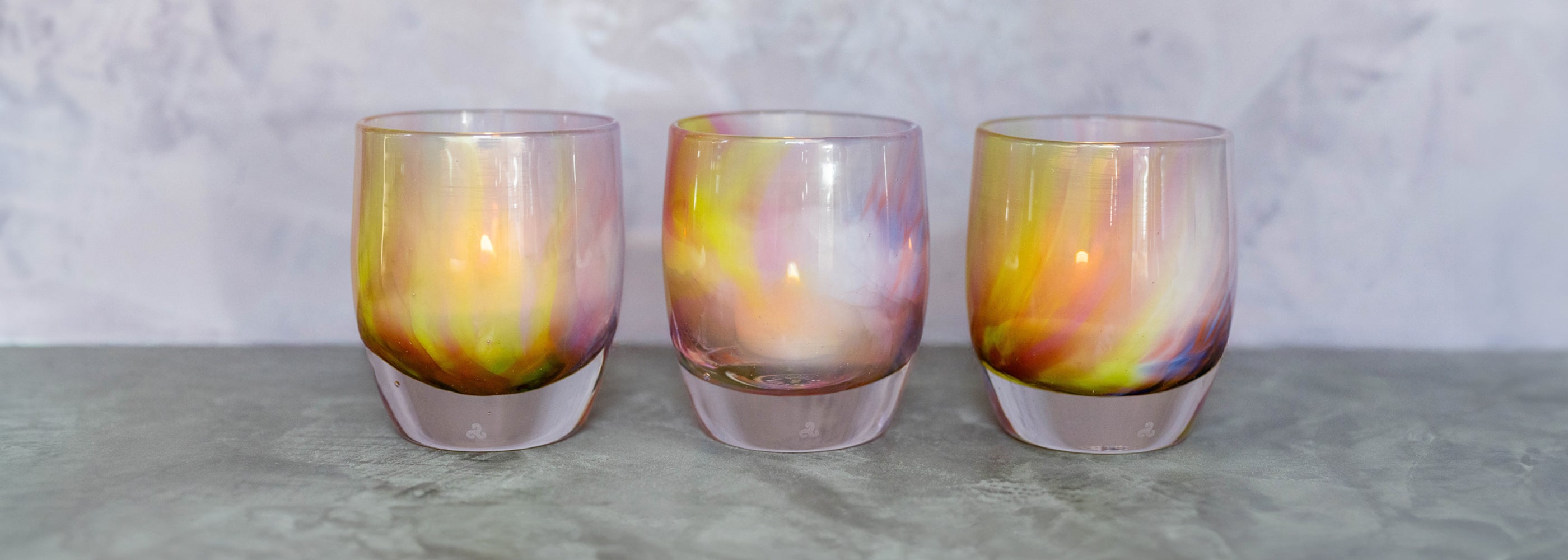make a wish glassybaby, a multi-color hand-blown candle holder on gray table with white background