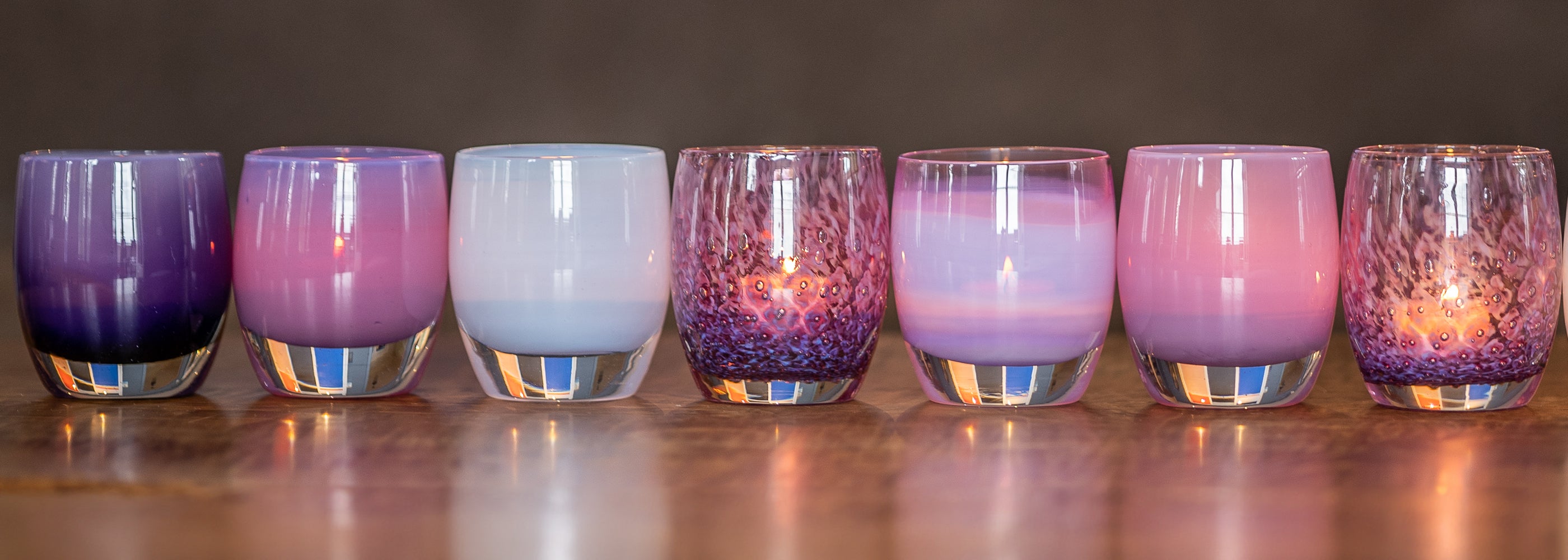 mother's day collection glassybaby hand-blown glass candle holders on wood bench.