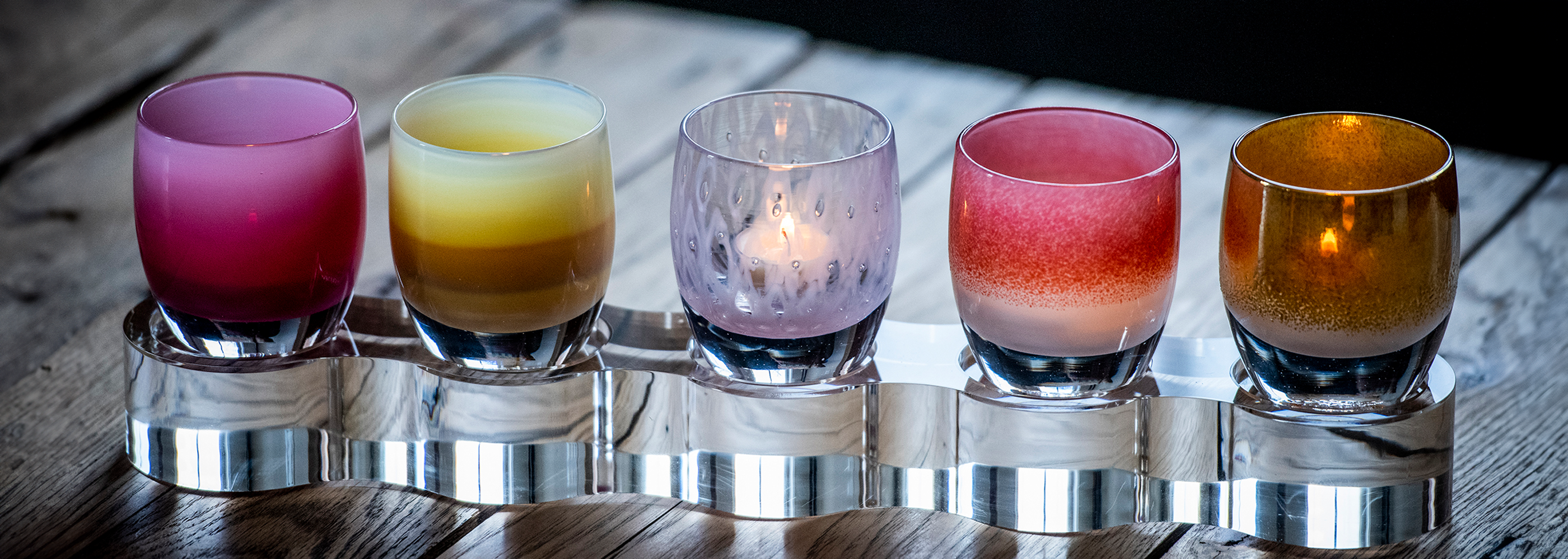 mother's day collection glassybaby hand-blown glass candle holders on wood bench.