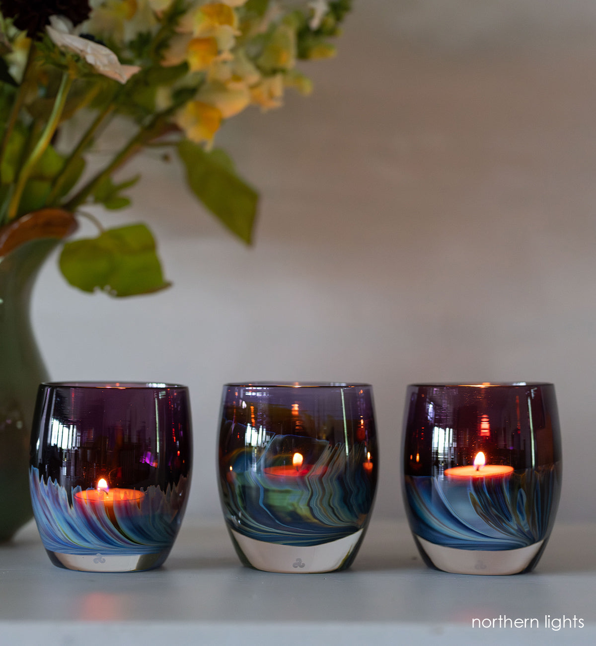three northern lights | purple with blue and green swooshing up from the bottom hand-blown glass votive with green vase with yellow flowers