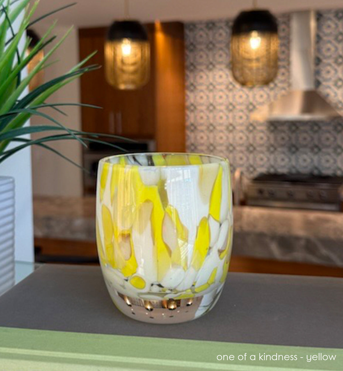 hand-blown glass candle holder with yellow and white patterns on a kitchen counter