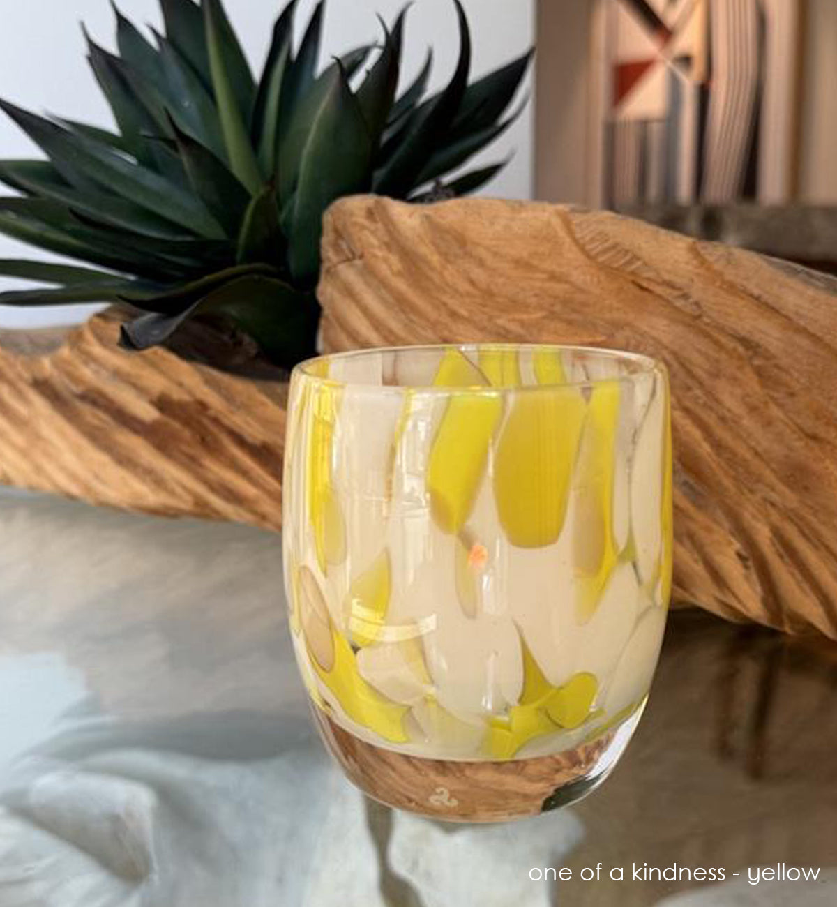 hand-blown glass candle holder with yellow and white design on a wooden surface