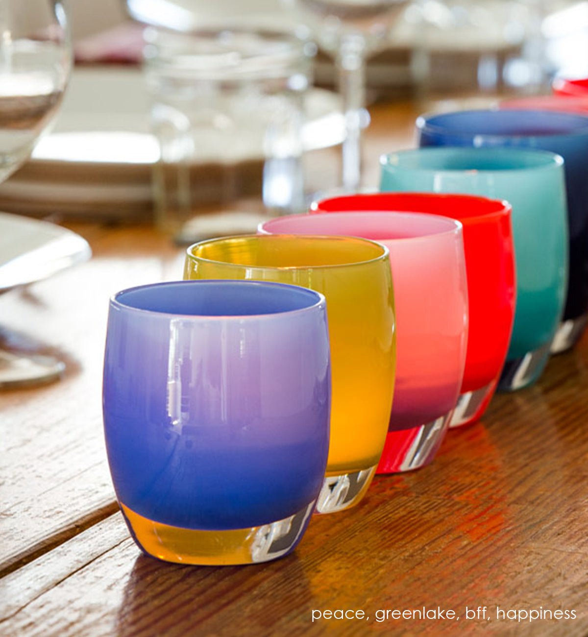 peace periwinkle blue hand-blown glass votive candle holder in a line of colorful glassybaby including greenlake, on a dining table.