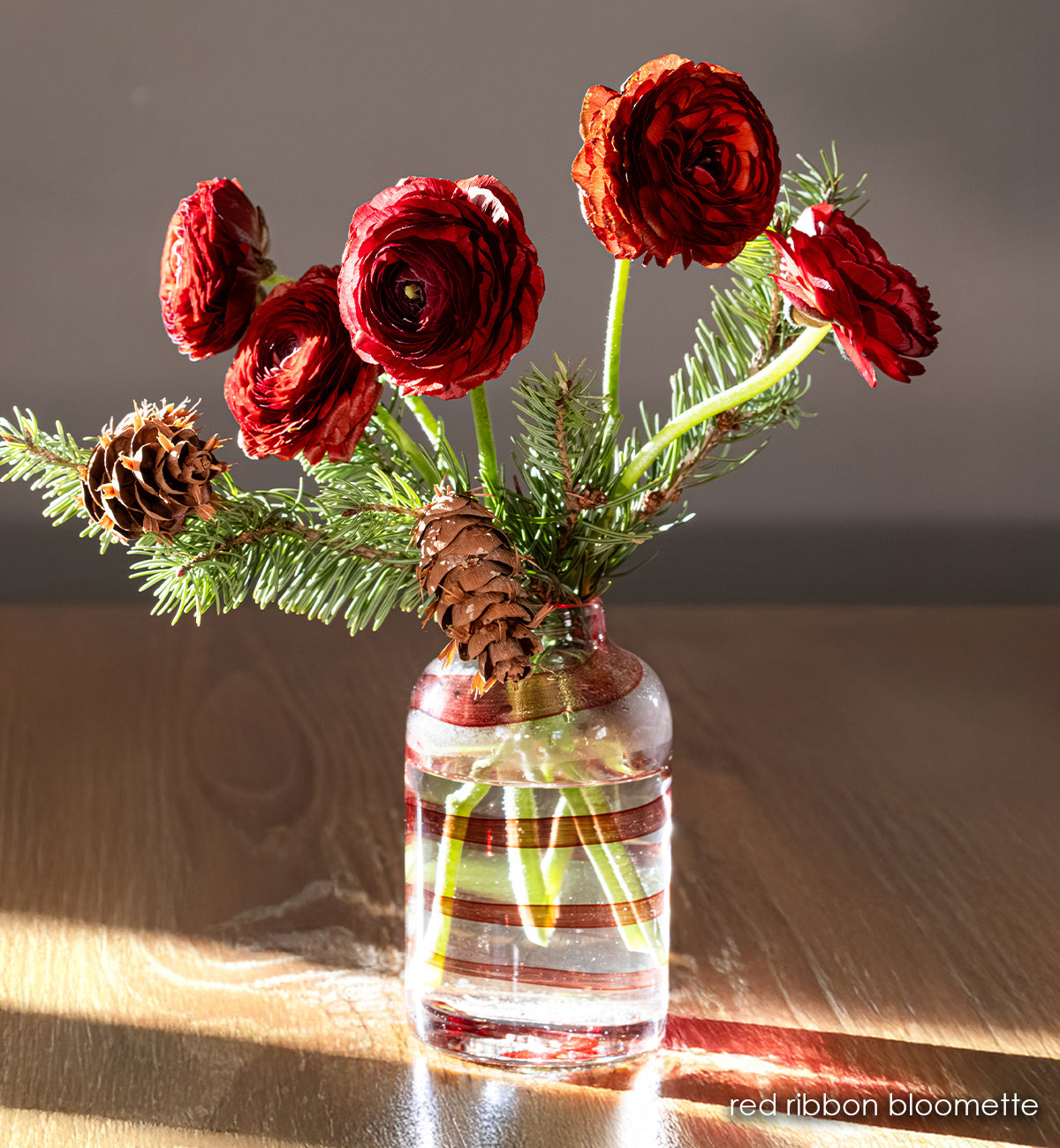 clear handblown glass bloomette with red twisted around it. with red flowers in vase.