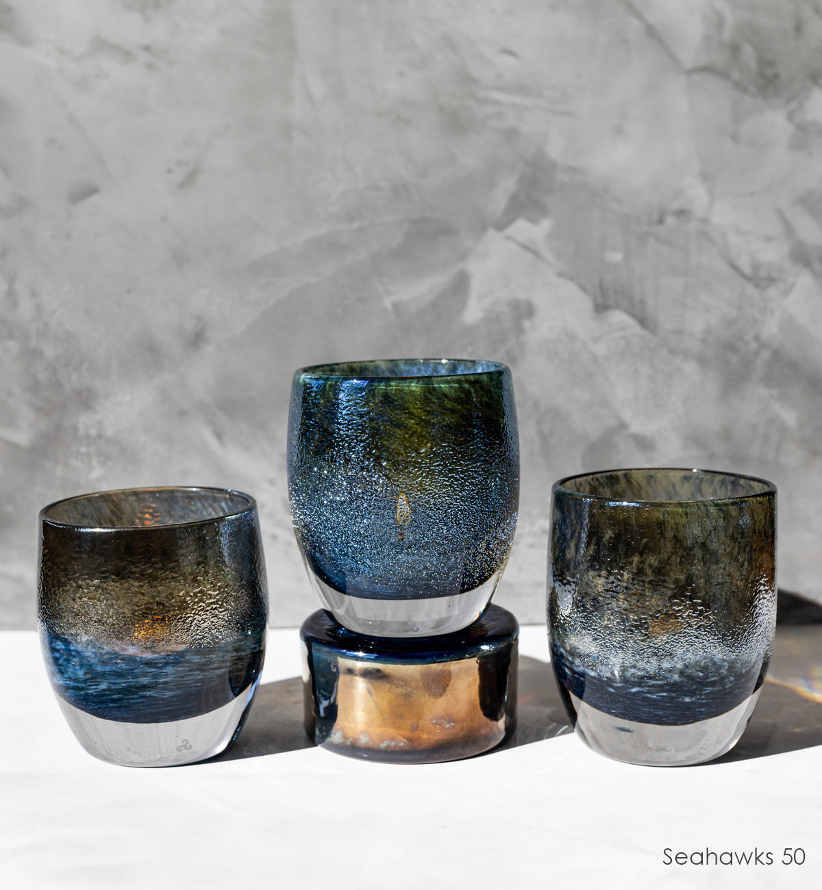 three Seahawks '50', navy and metallic, hand-blown glass votive candle holders on on a pedestal