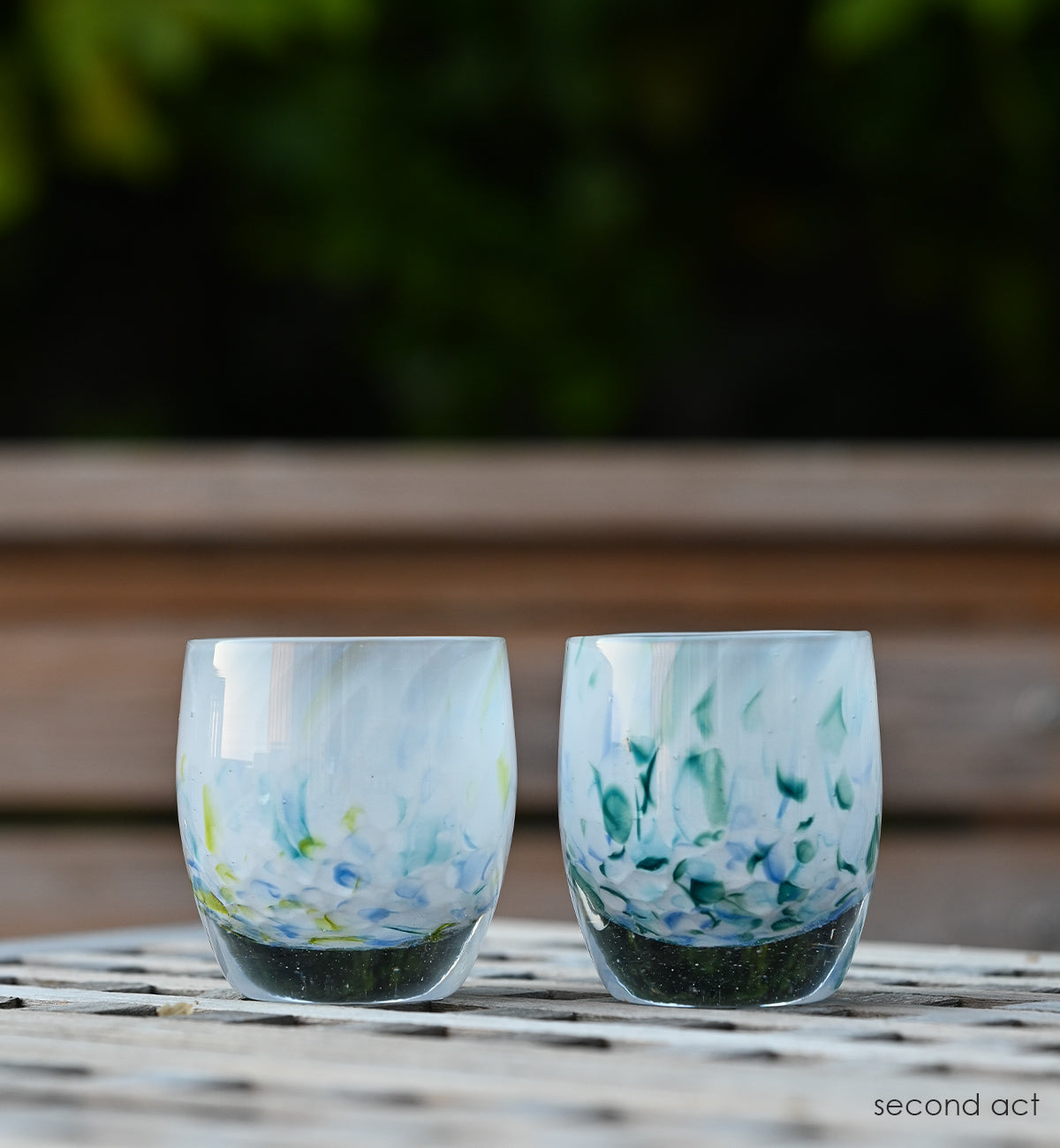 two second act hand-blown glass votive candle holders made from recycled glass from 43 colors, out a backyard patio table.