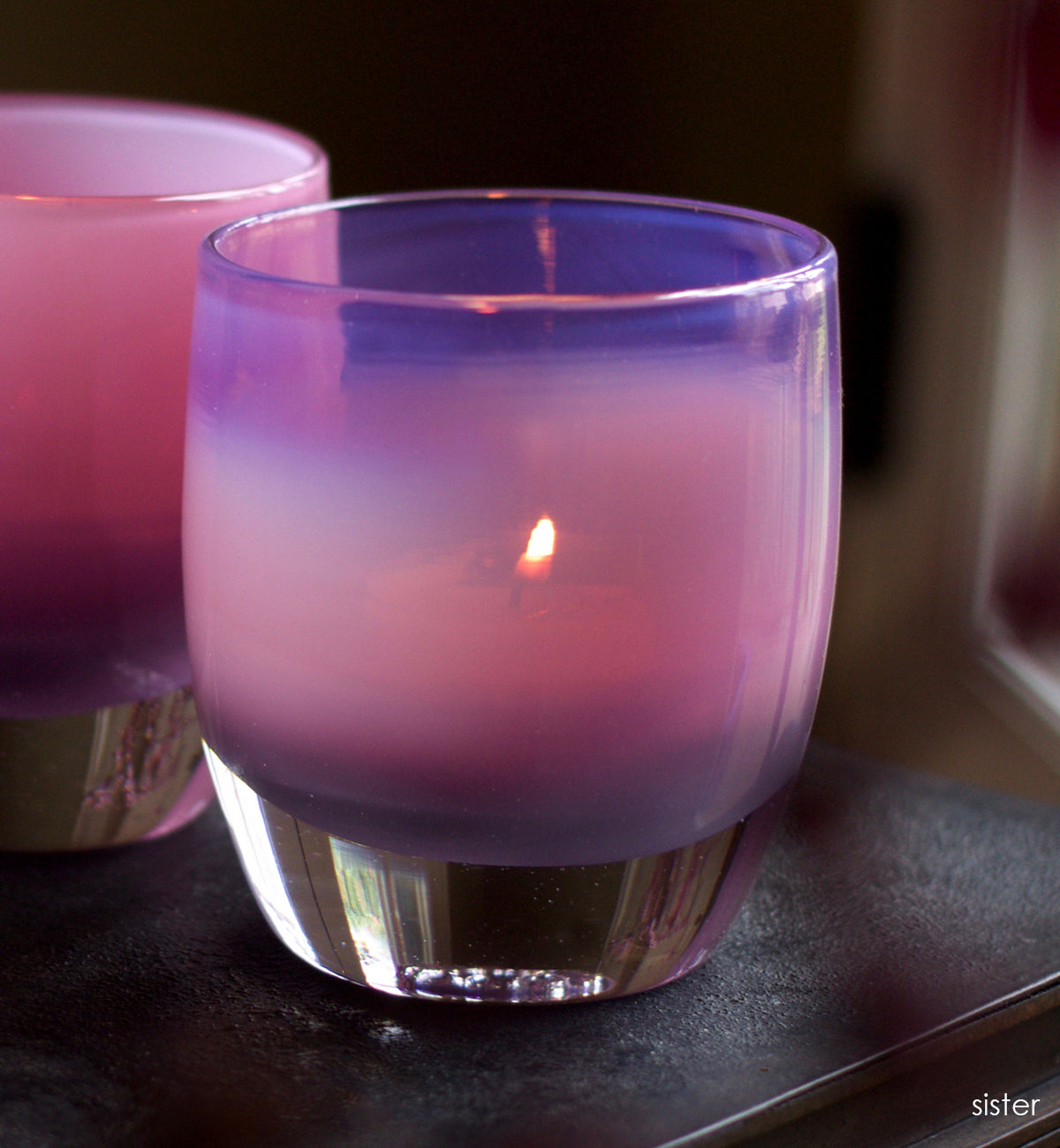 sister mauve purple hand-blown glass votive candle holder next to mom on a dark surface.