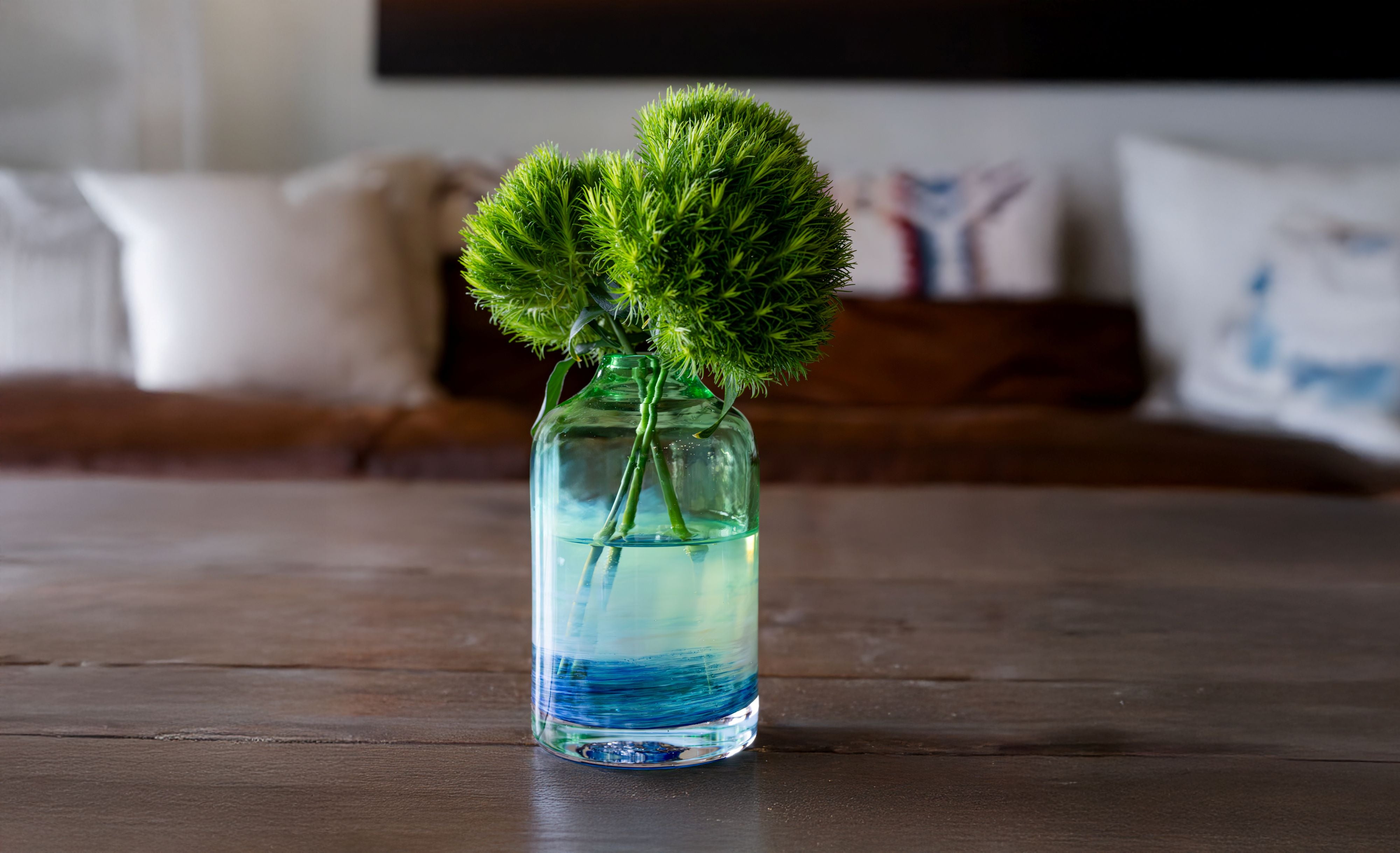 glassybaby bloomette transparent glass vase with blue and white accents on a wooden table with flowers inside the vase