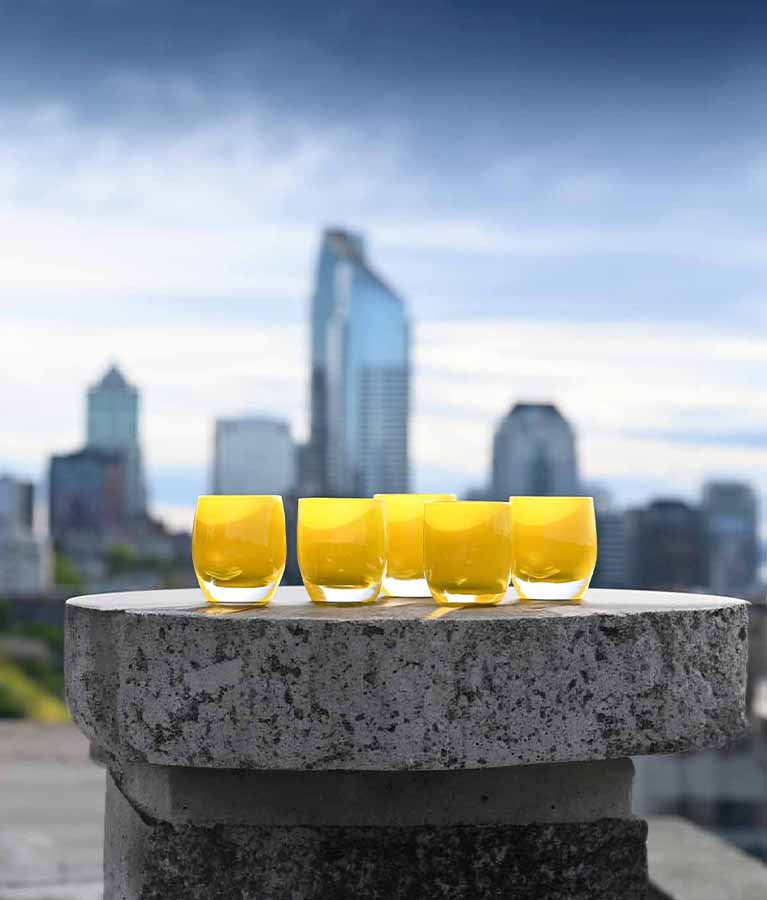 sunshine, yellow hand-blown glass votive candle holder, overlooking a metropolitan skyline.