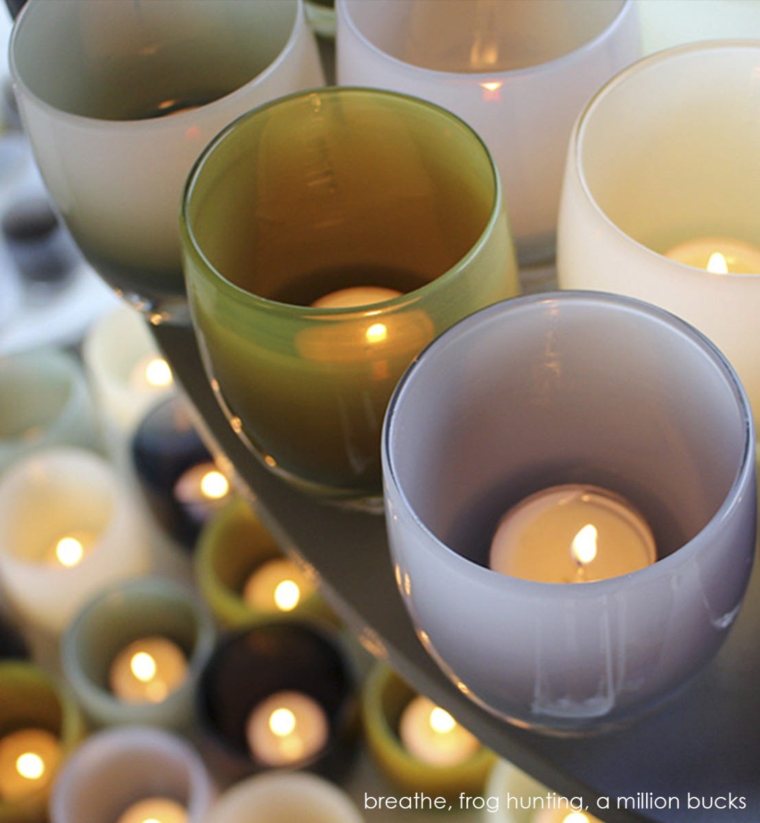 a million bucks light grey hand-blown glass votive candle holder grouped with breathe and frog hunting in a glassybaby display.