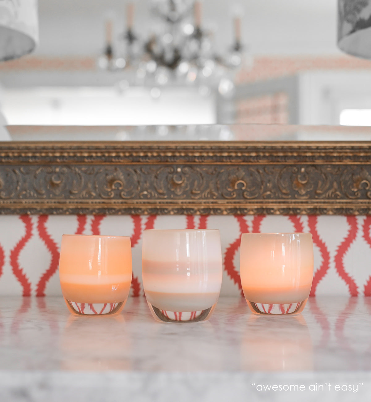 awesome ain't easy sandy yellow hand-blown glass votive candle holder on a marble mantle with a mirror in background.