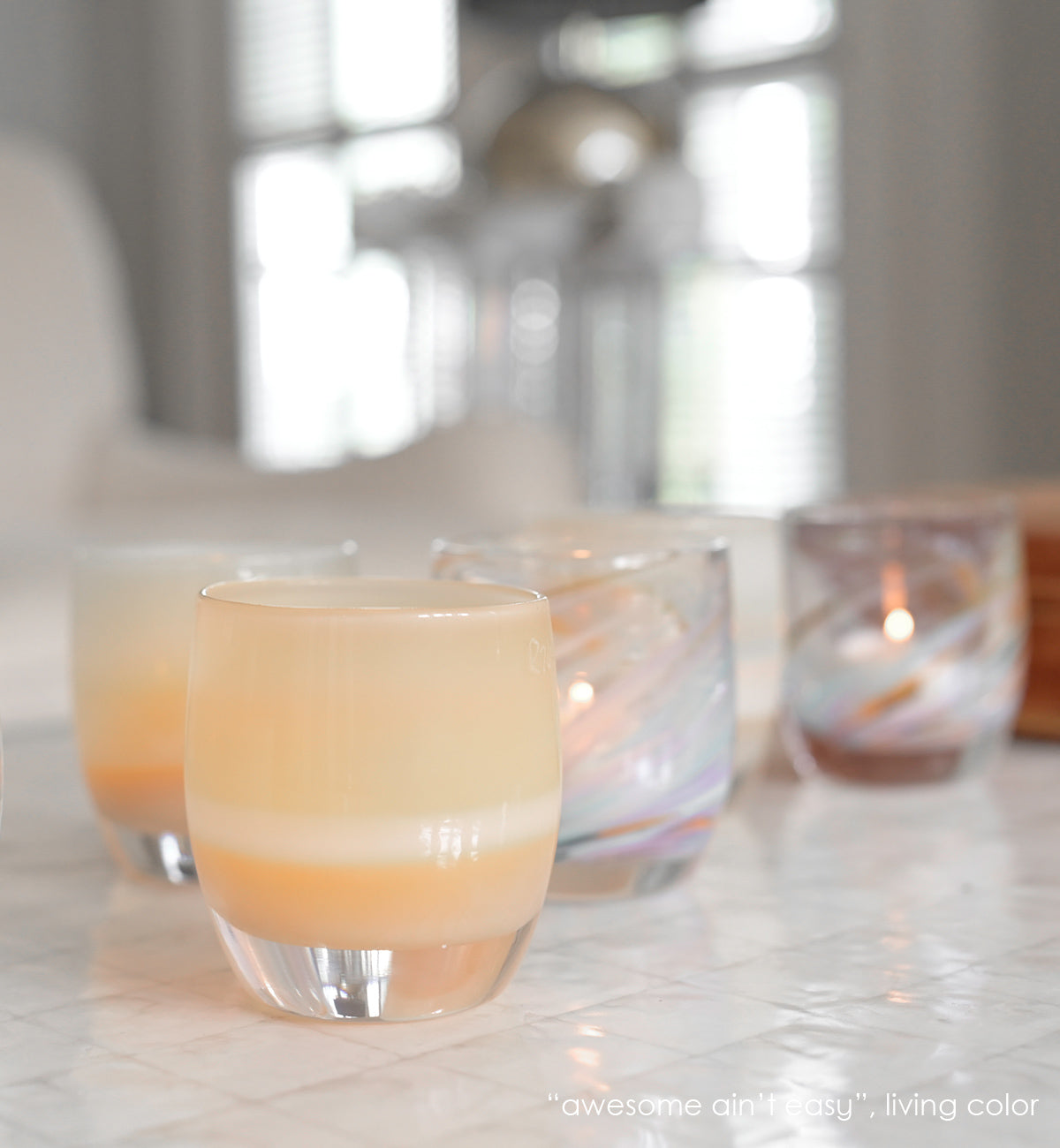 awesome ain't easy sandy yellow hand-blown glass votive candle holder with living color on a tile kitchen counter.