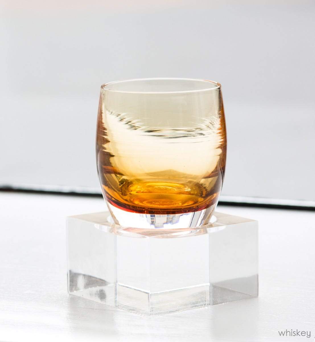 acrylic square baby holding whiskey in a white setting.