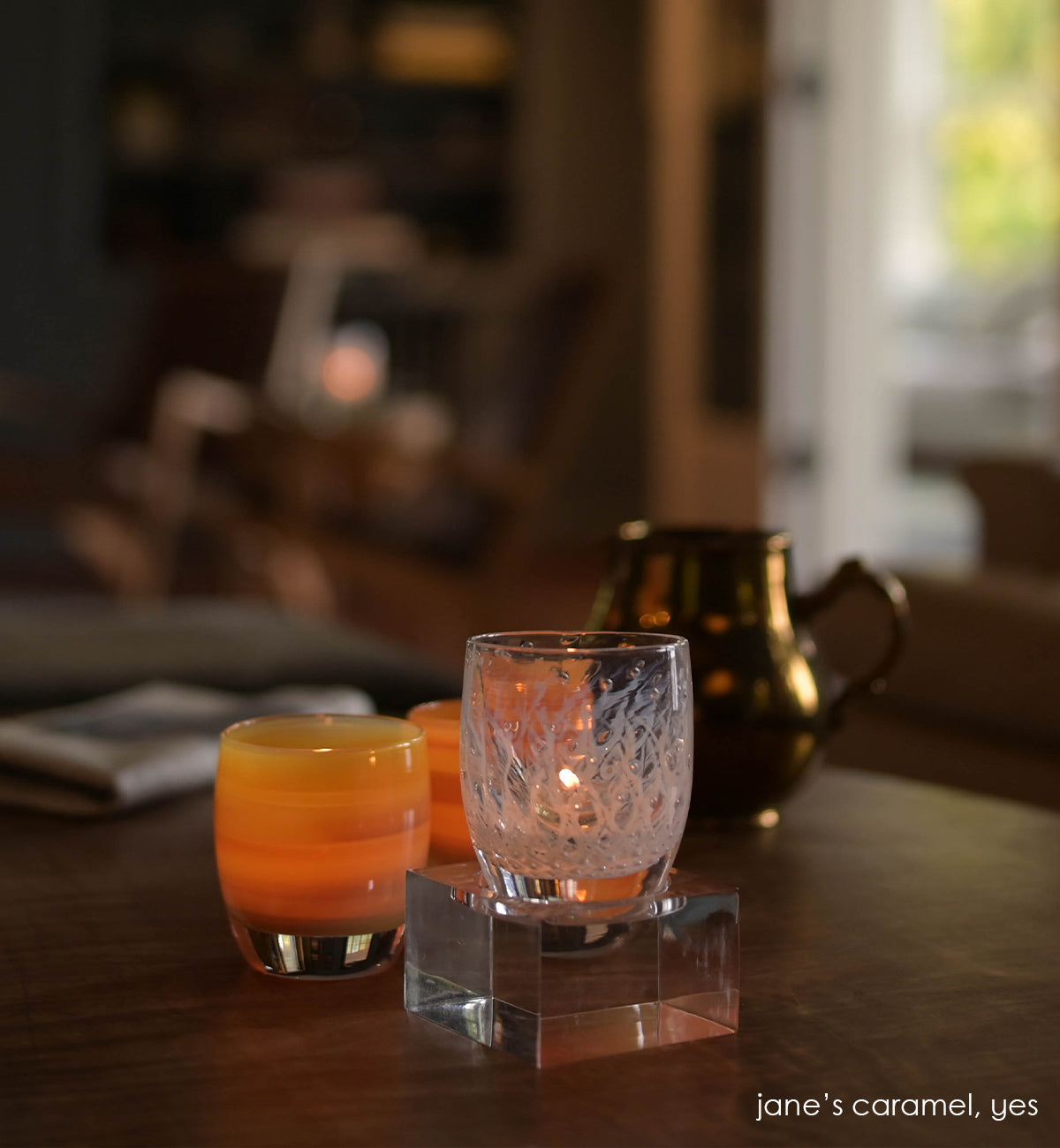 acrylic square baby stand holding yes, with two jane's caramel below on a wood kitchen table.