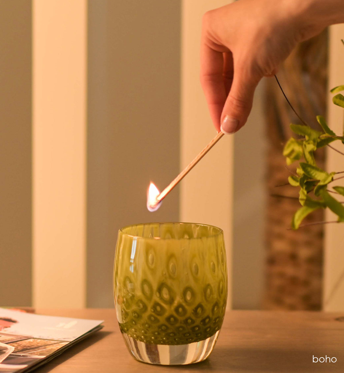 boho olive green bubble hand-blown glass votive candle holder with a lit match above to light its tealight.