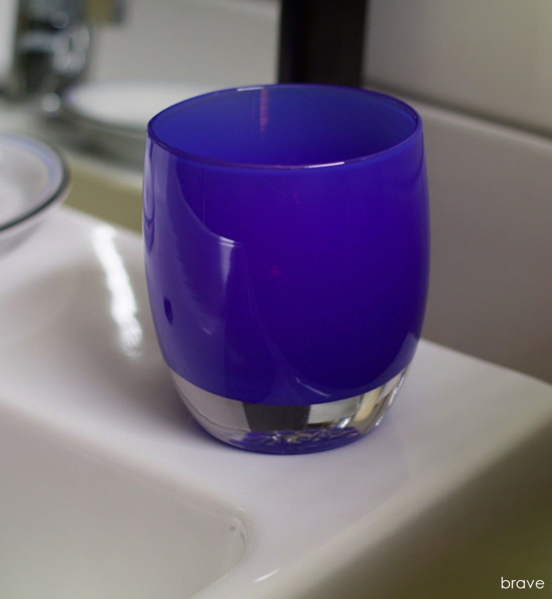 brave egyptian blue hand-blown glass votive candle holder sitting on a bathroom sink.