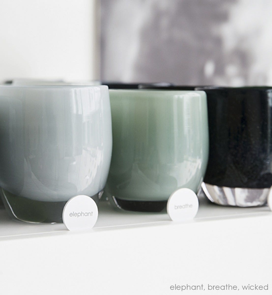 breathe sea green hand-blown glass votive candle holder next to elephant and wicked on a glassybaby shelf.