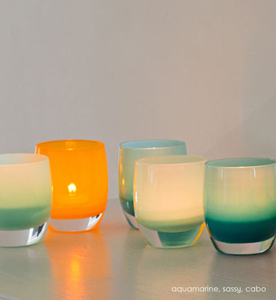 cabo opaque blue hand-blown glass votive candle holder. Paired with aquamarine and sassy on an indoor table.