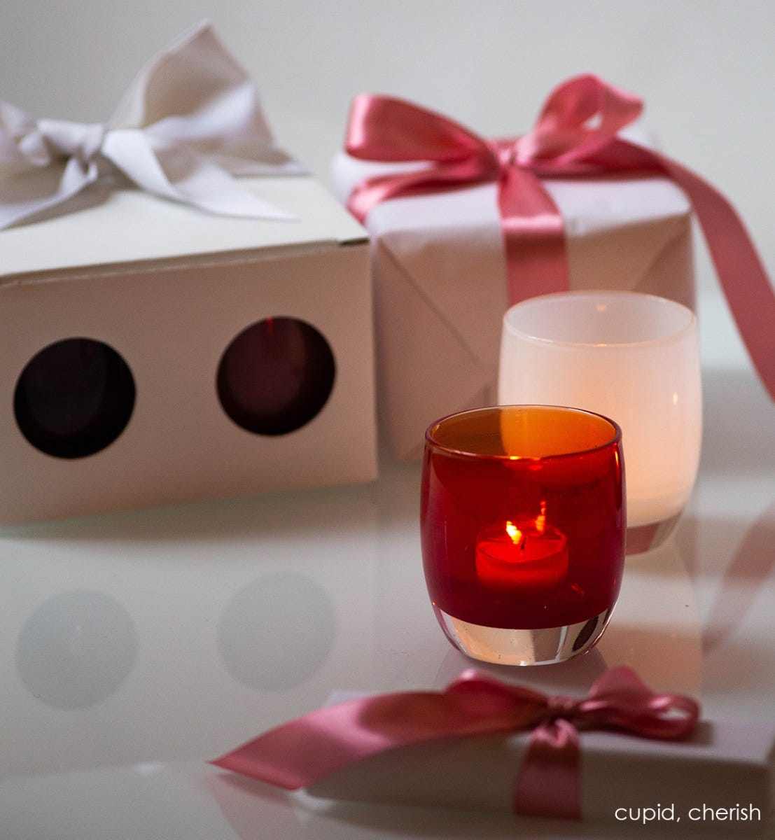 cupid transparent red hand-blown glass votive candle holder. Paired with cherish.