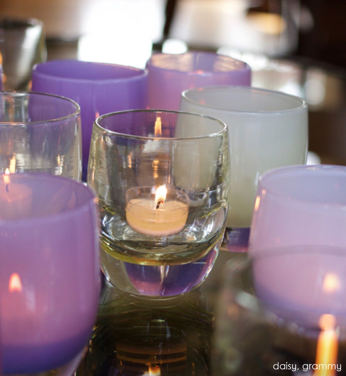 daisy transparent crystal yellow hand-blown glass votive candle holder. Paired with grammy on a reflective surface.