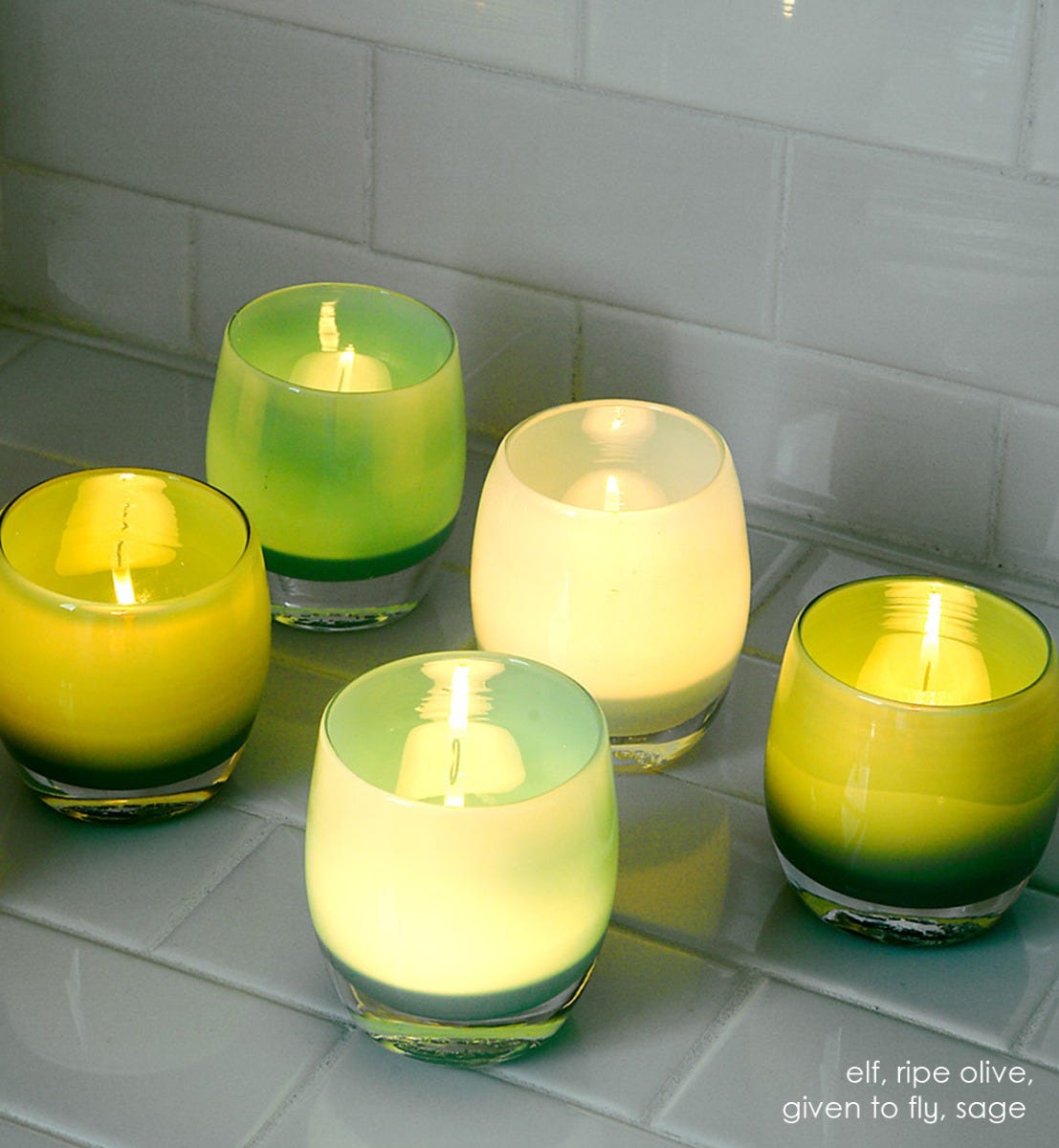 elf opaque light green hand-blown glass votive candle holder. Paired with ripe olive, given to fly, and sage on sage colored tile.