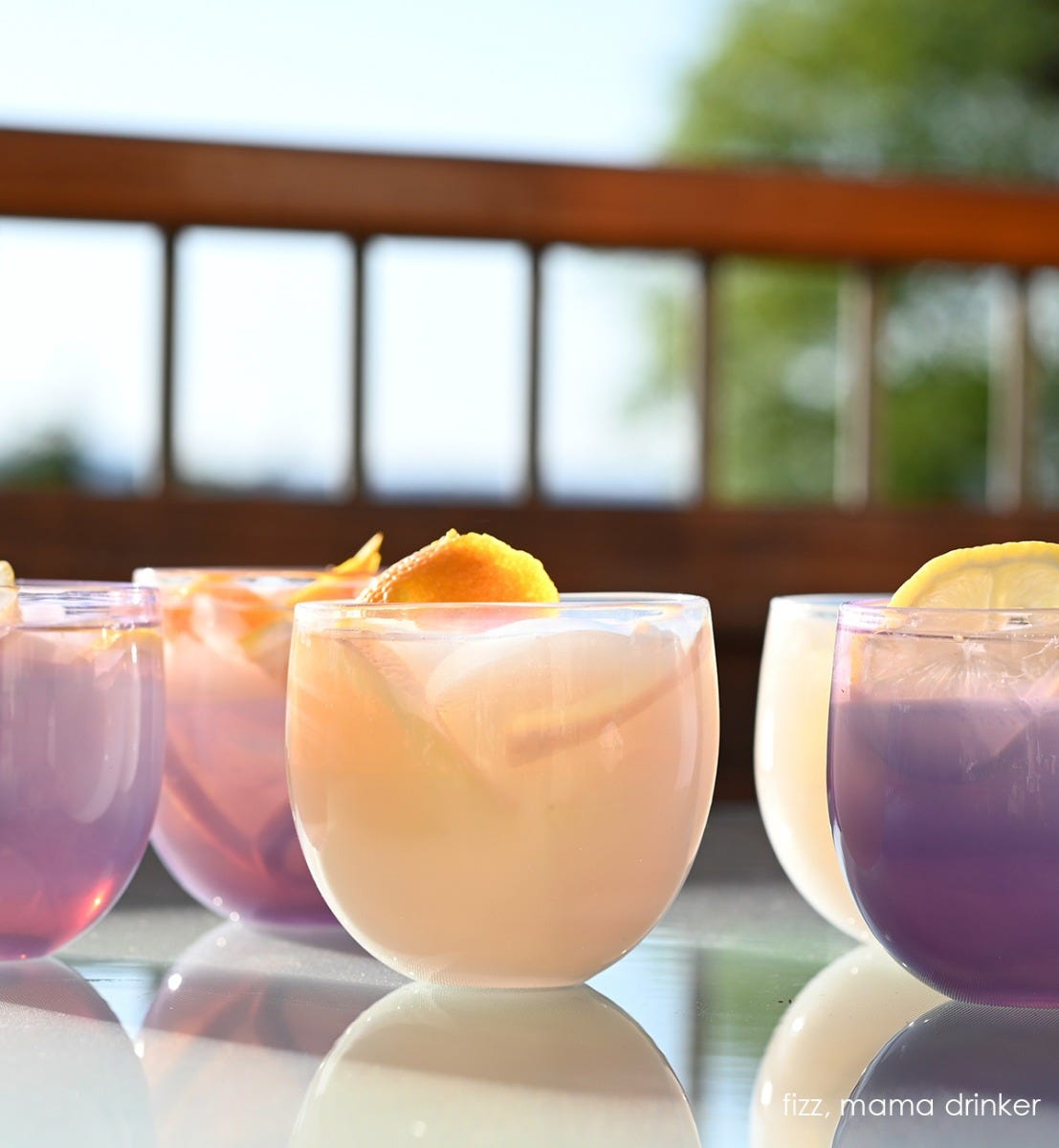 fizz drinkers, white hand-blown drinking glasses with mama drinkers on a sun deck, all filled with liquid and orange peel.