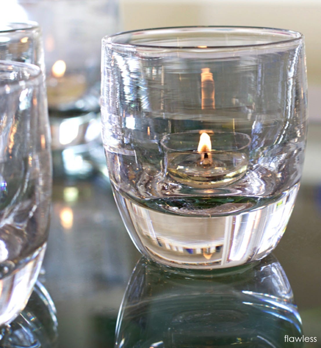 flawless transparent crystal clear hand-blown glass votive candle holder on a reflective surface.