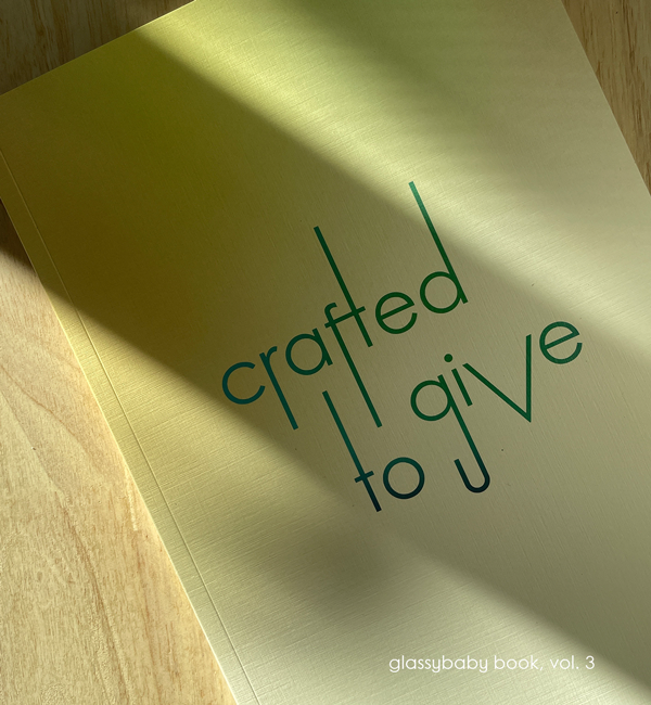 coffee table book of glassybaby volume three on a light wood table with sunshine peaking through.
