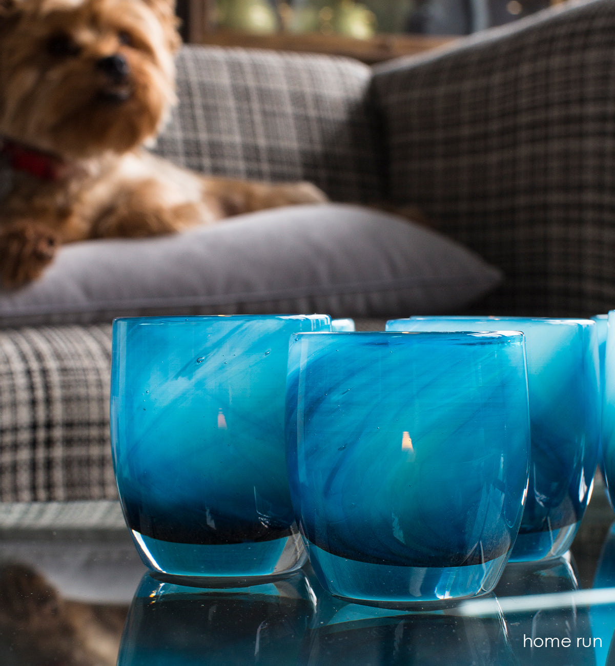 home run blue swirl, hand-blown glass votive candle holder. On a coffe table next to a small dog on a couch.