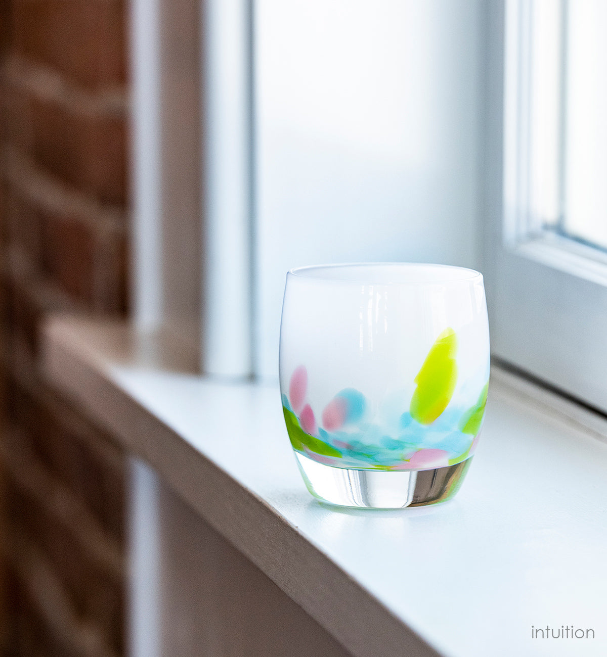 intuition blue, green and pink petals of color at the base of a white, hand-blown glass votive candle holder