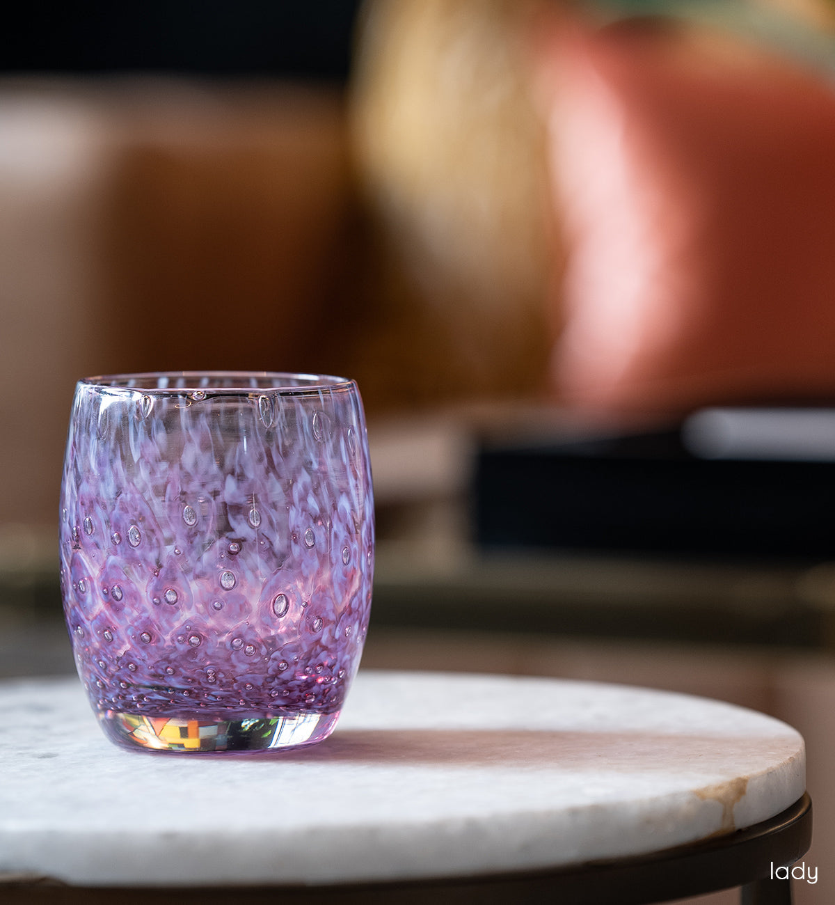 lady purple bubble, hand-blown glass votive candle holder on a circular marble living room table.